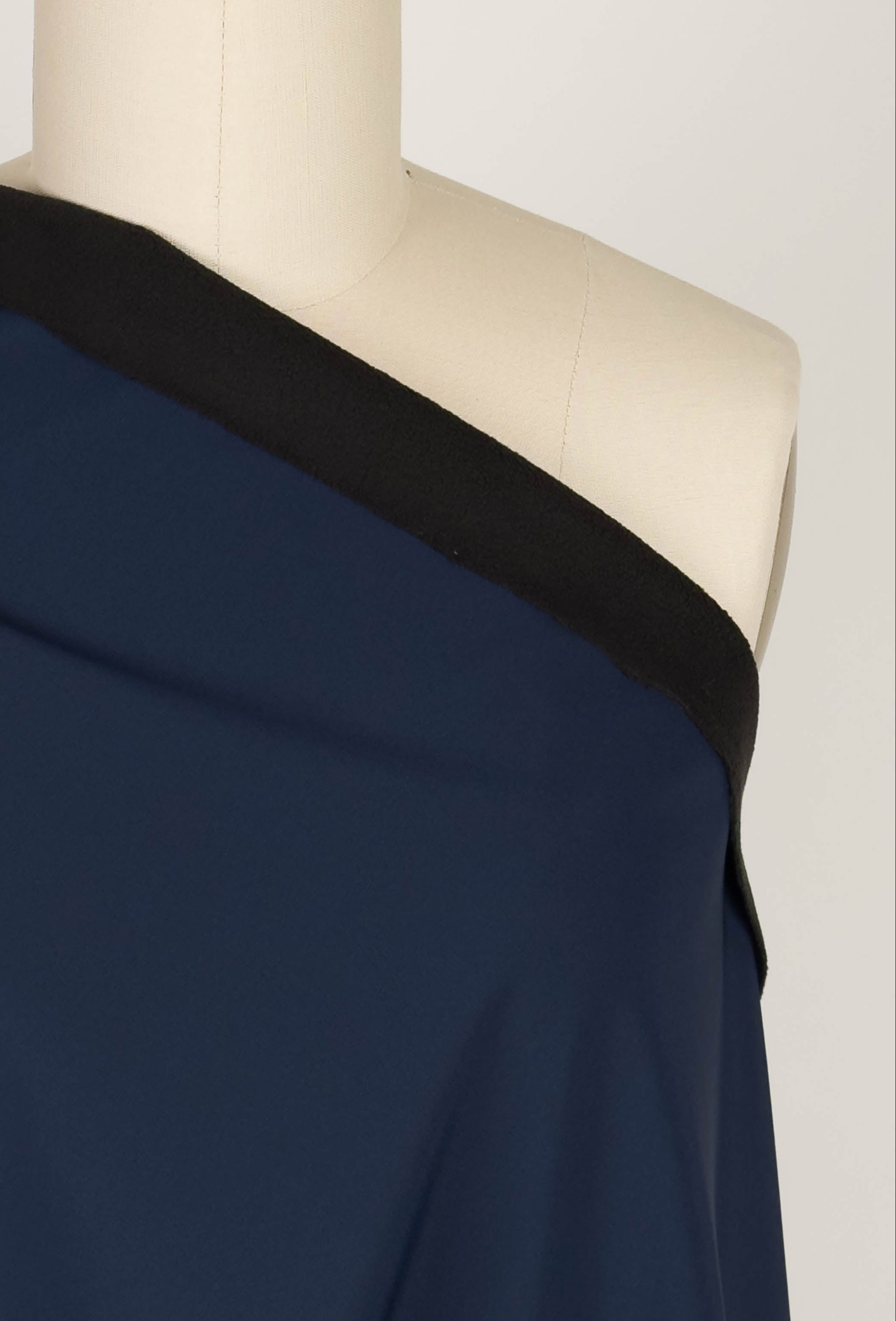 Navy blue softshell fabric draped over a mannequin on a plain background